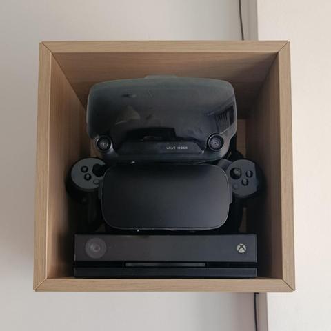A wooden square-shaped shelf with a Kinect, Oculus Rift CV1, and a Valve Index stacked on top of each other inside it. The Rift has each of its controllers on its sides.